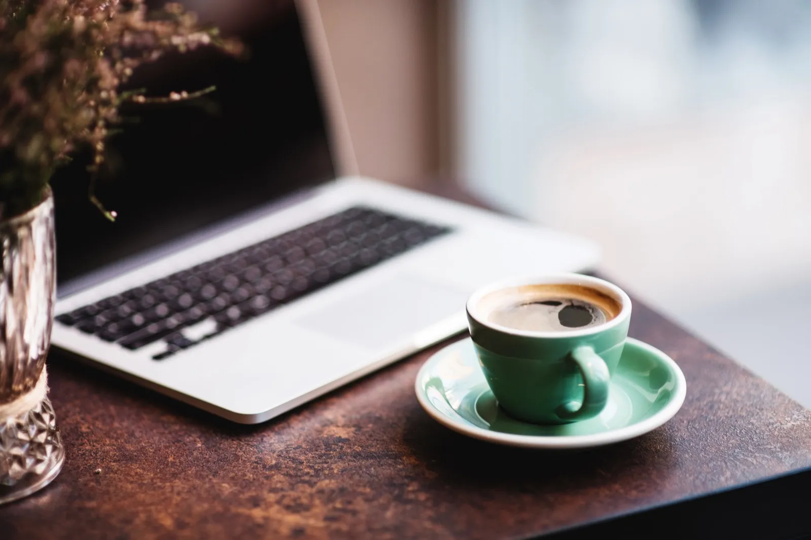 Coffee and laptop on a table by a window